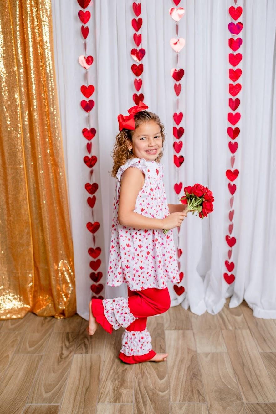 VALENTINA - Hearts Smock The VALENTINA 2-Piece Set features a smocked panel adorned with heart embroidery, ruffle accents, and a bright, tri-color combination of red, pink, and white. Made of pure cotton, this pants set ensures breathable comfort and a soft touch.